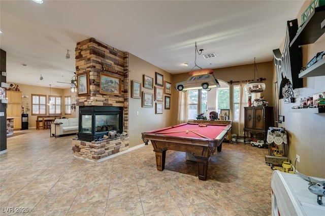 game room featuring a wealth of natural light, pool table, a stone fireplace, and visible vents