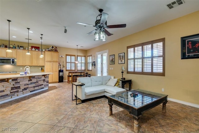 living room with visible vents, ceiling fan, baseboards, and light tile patterned flooring