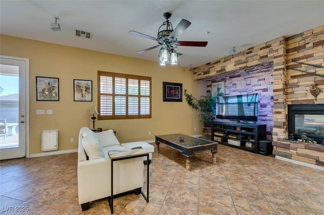 tiled living area featuring ceiling fan, a fireplace, visible vents, and baseboards