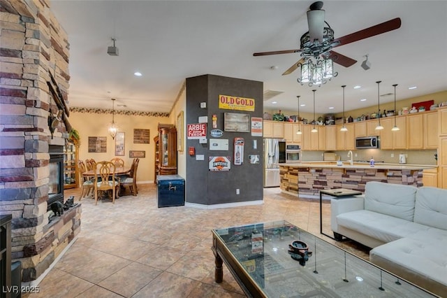 living area featuring light tile patterned floors, a stone fireplace, a ceiling fan, and recessed lighting