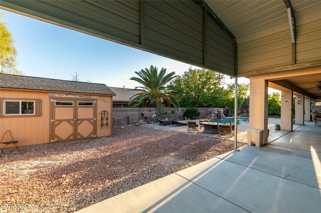 view of patio / terrace featuring a fenced in pool, a storage unit, an outdoor fire pit, fence, and an outdoor structure