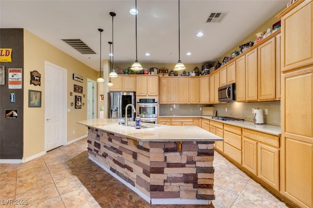 kitchen with appliances with stainless steel finishes, visible vents, a sink, and light brown cabinetry