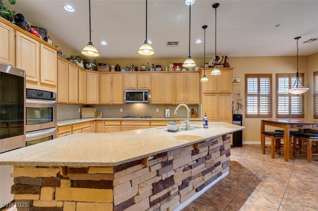 kitchen featuring stainless steel appliances, light brown cabinets, a sink, and decorative backsplash