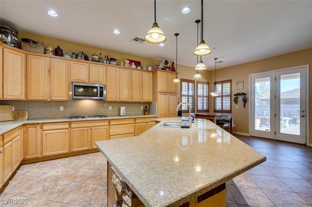 kitchen with appliances with stainless steel finishes, a sink, and light brown cabinetry