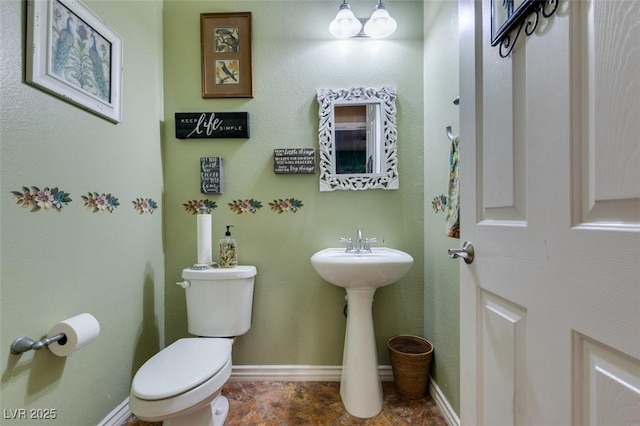 bathroom featuring toilet and baseboards