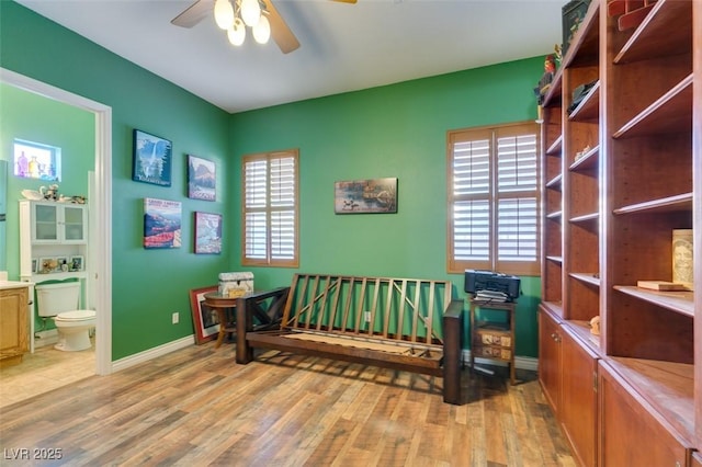 bedroom featuring multiple windows, ensuite bath, light wood-style flooring, and baseboards