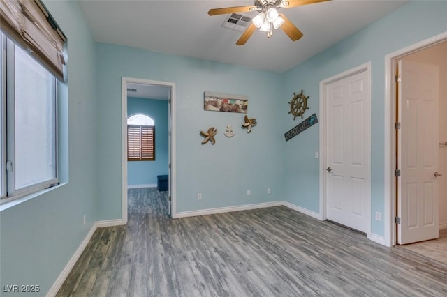 spare room with visible vents, ceiling fan, baseboards, and wood finished floors