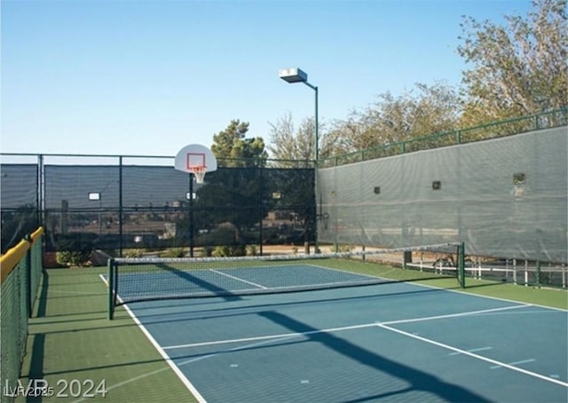 view of tennis court with community basketball court and fence