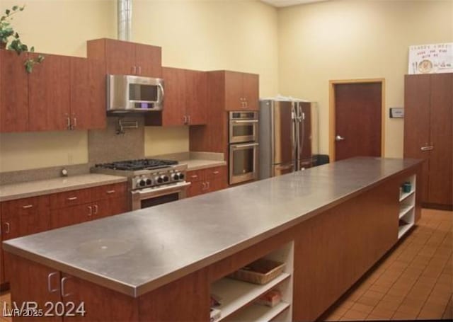 kitchen featuring brown cabinets, stainless steel countertops, appliances with stainless steel finishes, and open shelves