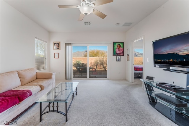 living room featuring carpet floors, visible vents, plenty of natural light, and a ceiling fan