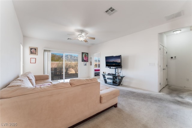 living room featuring carpet floors, visible vents, and a ceiling fan