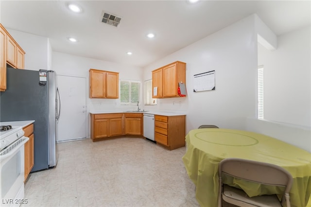 kitchen featuring white appliances, visible vents, light countertops, light floors, and a sink