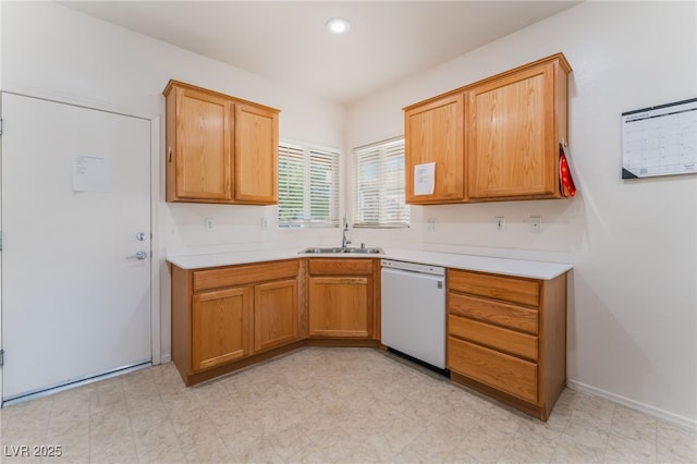 kitchen with baseboards, light countertops, dishwasher, and a sink