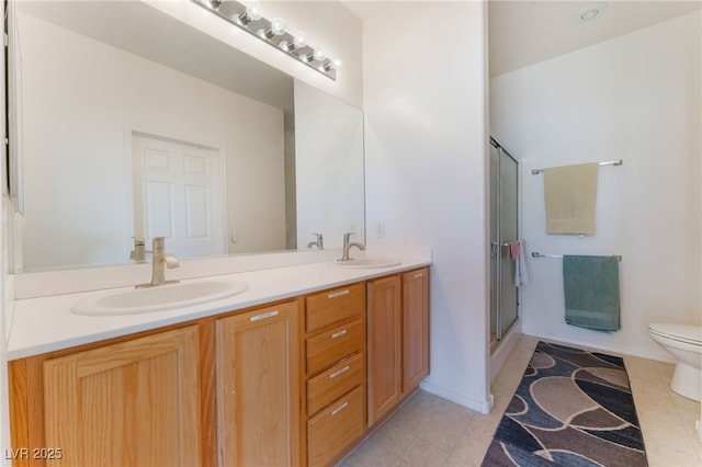 bathroom with double vanity, a sink, toilet, and tile patterned floors