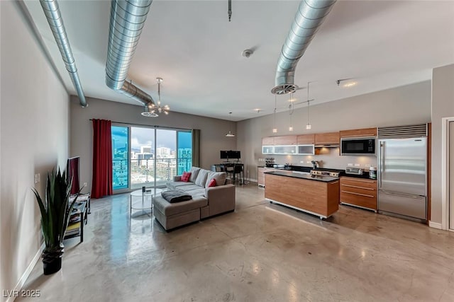 living area featuring finished concrete flooring, baseboards, and an inviting chandelier