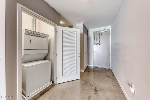 laundry area with laundry area, stacked washer / dryer, and baseboards