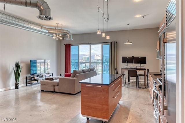 kitchen featuring dark countertops, a center island, concrete floors, and stainless steel range with gas cooktop