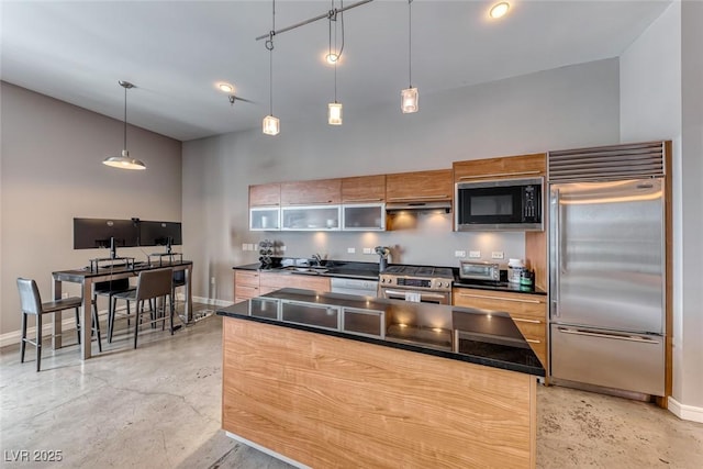 kitchen featuring built in appliances, under cabinet range hood, a high ceiling, baseboards, and dark countertops