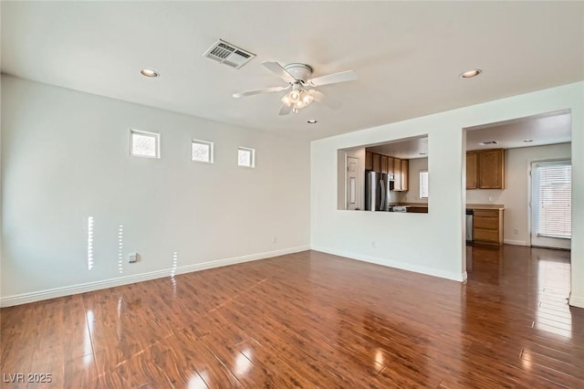 unfurnished living room with dark wood-style floors, baseboards, and visible vents