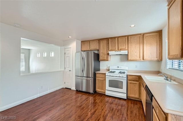 kitchen featuring dark wood-style flooring, light countertops, appliances with stainless steel finishes, a sink, and under cabinet range hood