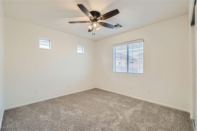 carpeted spare room featuring baseboards, visible vents, and a ceiling fan