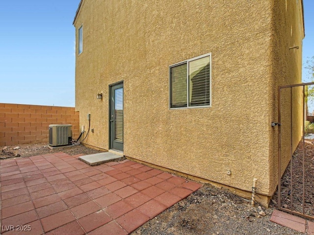 rear view of property with central AC, a patio, fence, and stucco siding