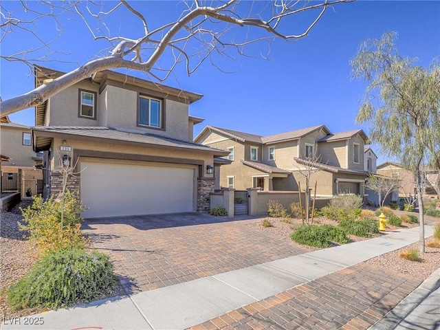 view of front of house featuring an attached garage, fence, stone siding, decorative driveway, and stucco siding