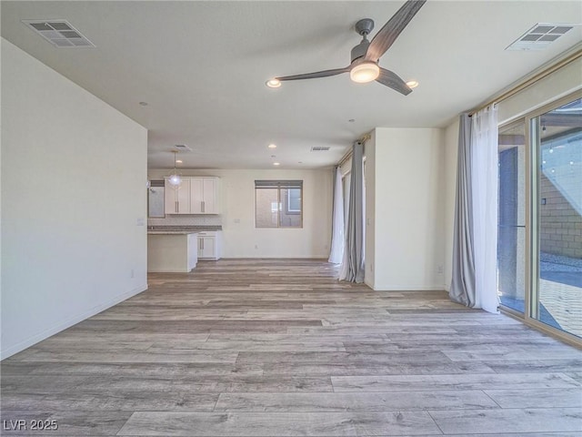 unfurnished living room featuring light wood-style flooring, plenty of natural light, and visible vents