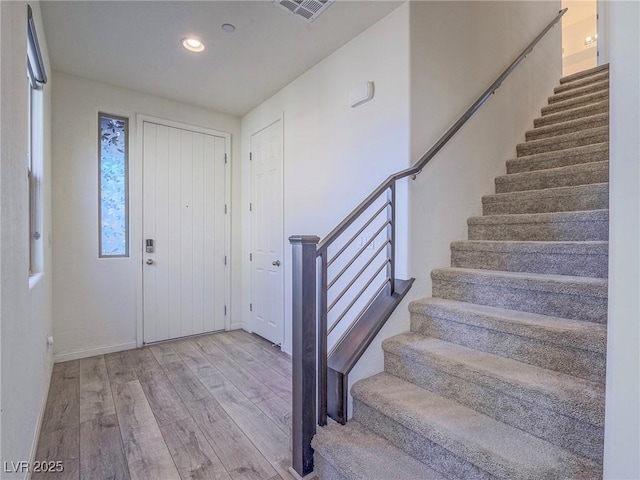 foyer entrance featuring recessed lighting, visible vents, stairway, and wood finished floors