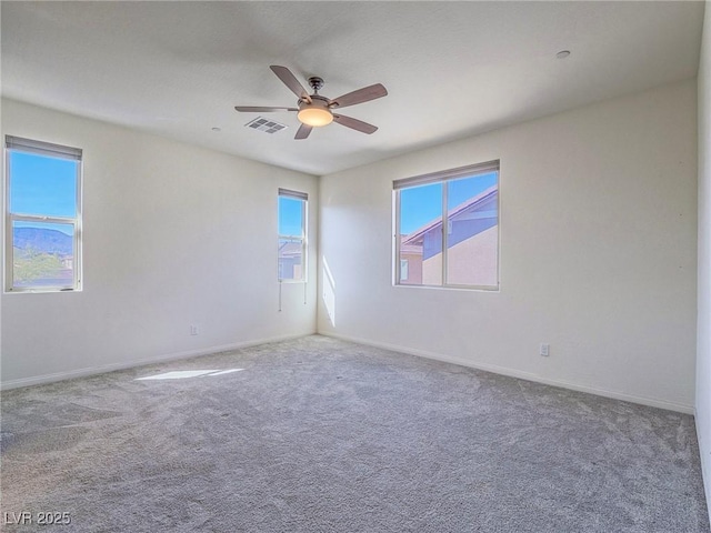 unfurnished room with carpet floors, plenty of natural light, visible vents, and a ceiling fan