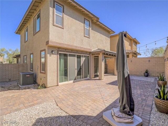 rear view of house featuring a patio, central air condition unit, a fenced backyard, and stucco siding