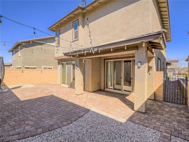 rear view of property with a patio, fence, a gate, and stucco siding