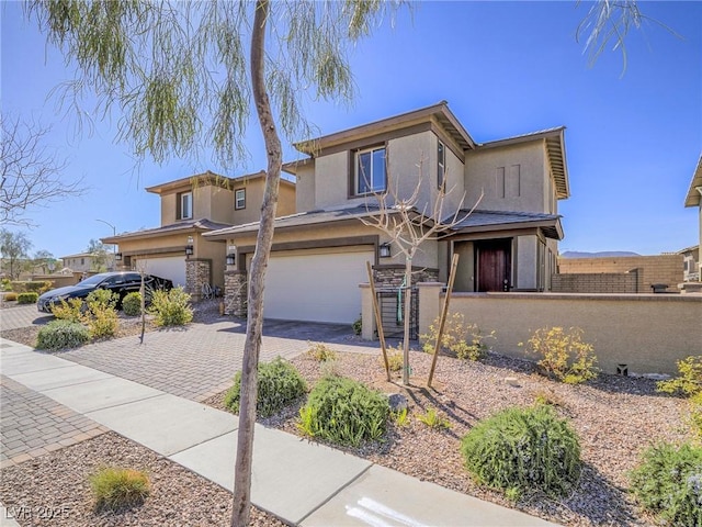 view of front of house featuring a garage, decorative driveway, fence, and stucco siding