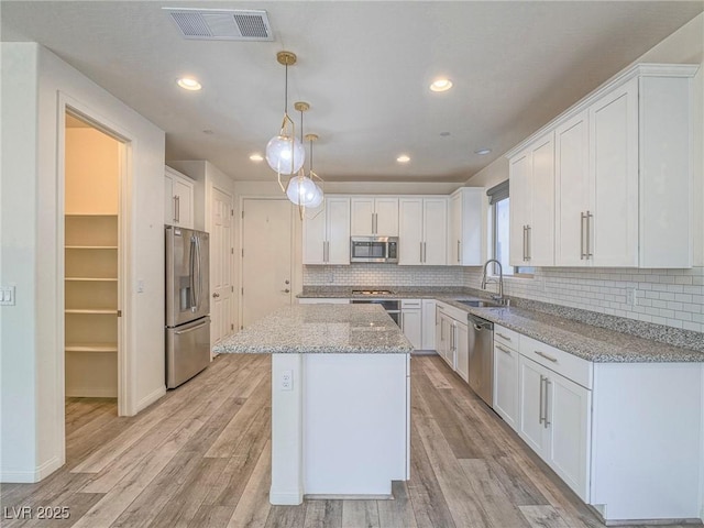 kitchen featuring visible vents, appliances with stainless steel finishes, white cabinets, and a sink