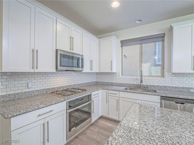 kitchen with appliances with stainless steel finishes, a sink, and white cabinets