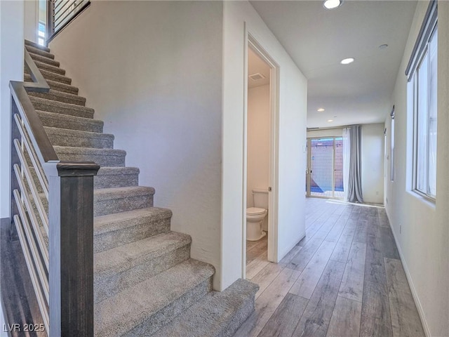 stairway with baseboards, wood finished floors, visible vents, and recessed lighting