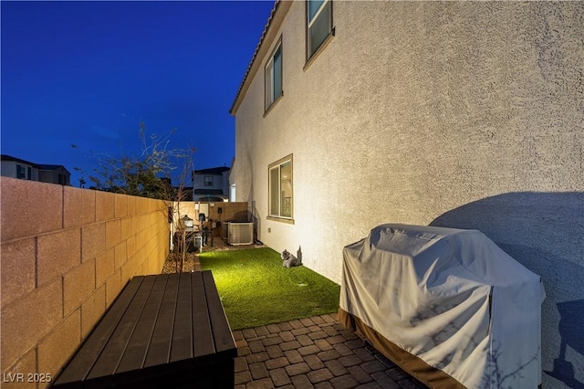 view of side of home with a fenced backyard, a yard, a patio area, central AC, and stucco siding