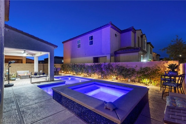 pool at twilight with a patio, a fenced backyard, an outdoor hangout area, an in ground hot tub, and a fenced in pool