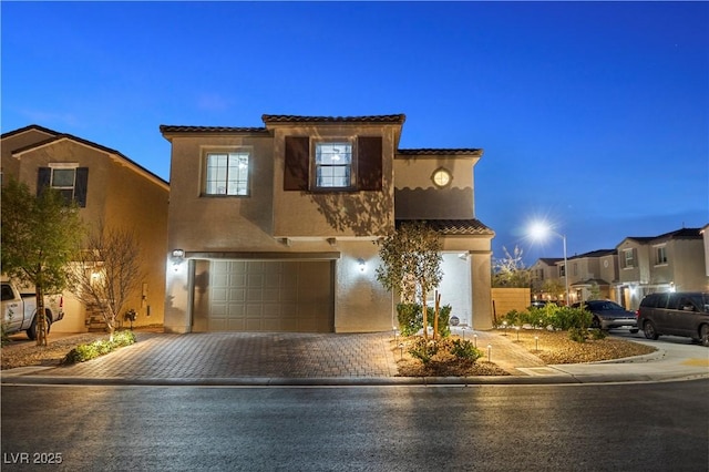 view of front of house featuring an attached garage, decorative driveway, and stucco siding