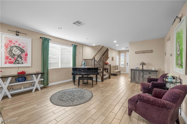 living room with stairs, a healthy amount of sunlight, visible vents, and wood finished floors