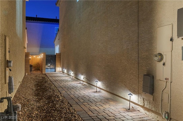 property exterior at night with a gate and stucco siding