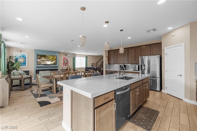 kitchen featuring visible vents, dishwashing machine, wood finish floors, stainless steel refrigerator with ice dispenser, and a sink