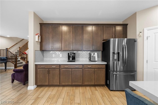 kitchen featuring light wood-style flooring, decorative backsplash, stainless steel refrigerator with ice dispenser, and light countertops