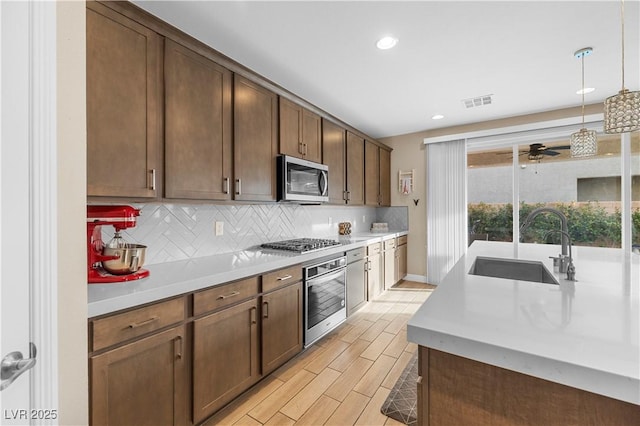 kitchen featuring stainless steel appliances, tasteful backsplash, a sink, and light countertops