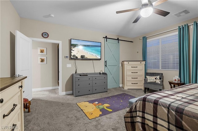 bedroom with a barn door, light colored carpet, a ceiling fan, baseboards, and visible vents