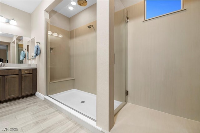 full bathroom with wood finish floors, a stall shower, and vanity