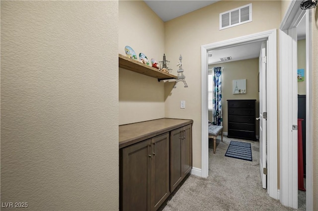 hallway with light carpet, baseboards, and visible vents