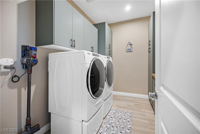 clothes washing area with cabinet space, independent washer and dryer, light wood-style flooring, and baseboards