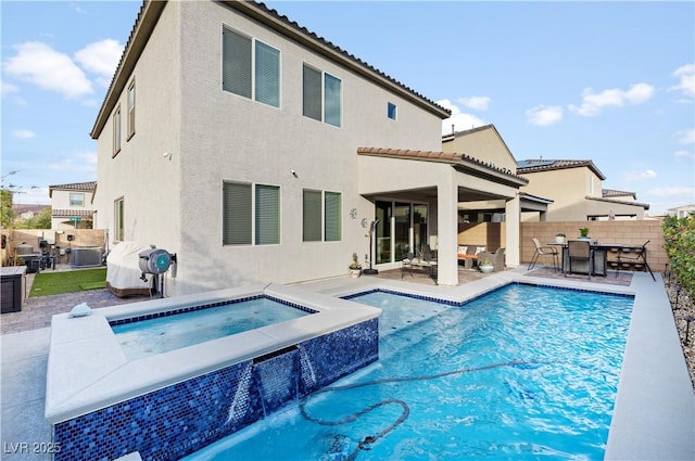 rear view of property featuring a fenced in pool, a patio, an in ground hot tub, fence, and stucco siding