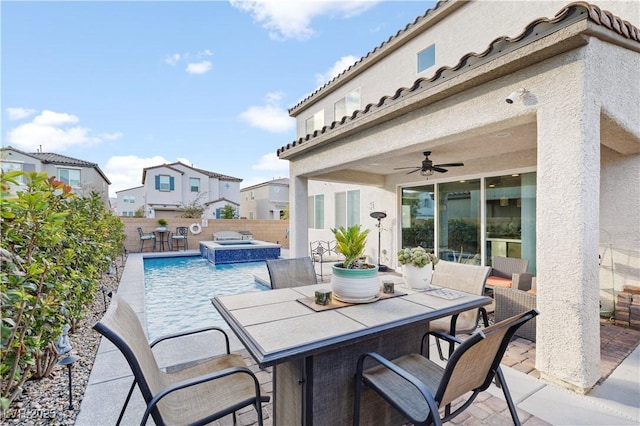 view of patio / terrace featuring a ceiling fan, a pool with connected hot tub, a fenced backyard, and outdoor dry bar